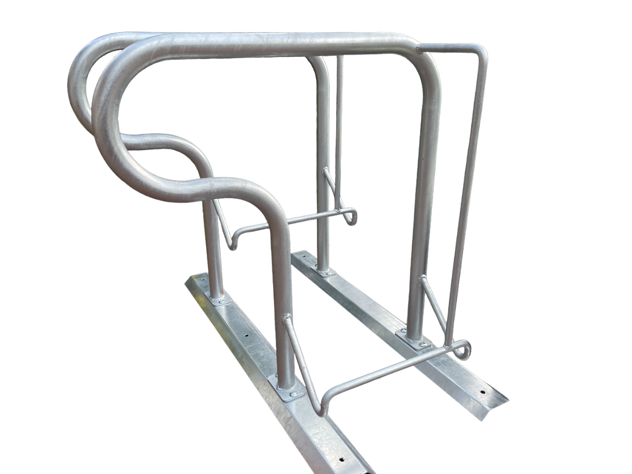 Das Bild zeigt eine Fahrrad-Abstellanlage aus verzinktem Metall mit zwei Halterungen. Die Konstruktion besteht aus bogenförmigen, runden Rohren auf stabilen Bodenplatten, geeignet zum Abstellen und Sichern von Fahrrädern. Die Halterungen haben unterschiedliche Höhen und ermöglichen das Einparken der Fahrräder nebeneinander. Die Metallstreben sind fest verschweißt und robust verarbeitet. Der Hintergrund ist weiß und neutral gehalten.
