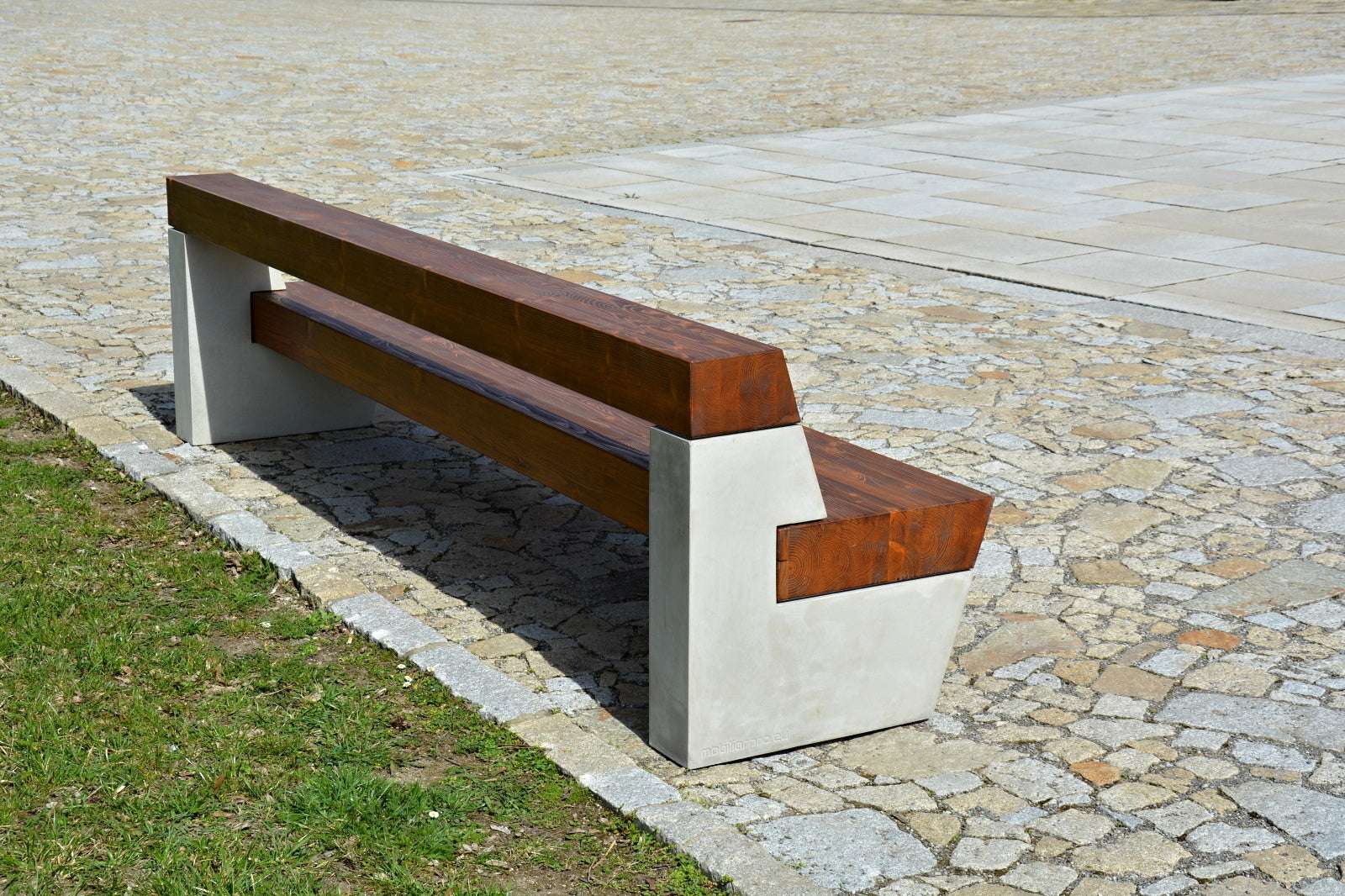 Moderne Bank mit Holzsitzfläche und Betonstützen auf Pflastersteinen im Freien installiert.