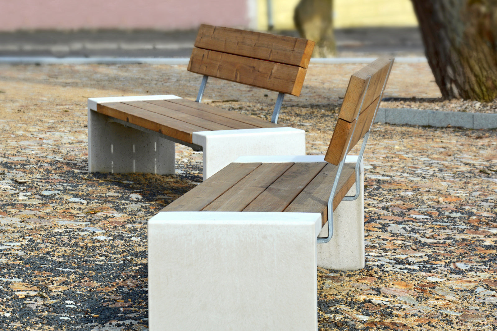 Holzbank mit Betonfüßen auf gepflastertem Platz, zwei Sitzplätze, modern und minimalistisch gestaltet.