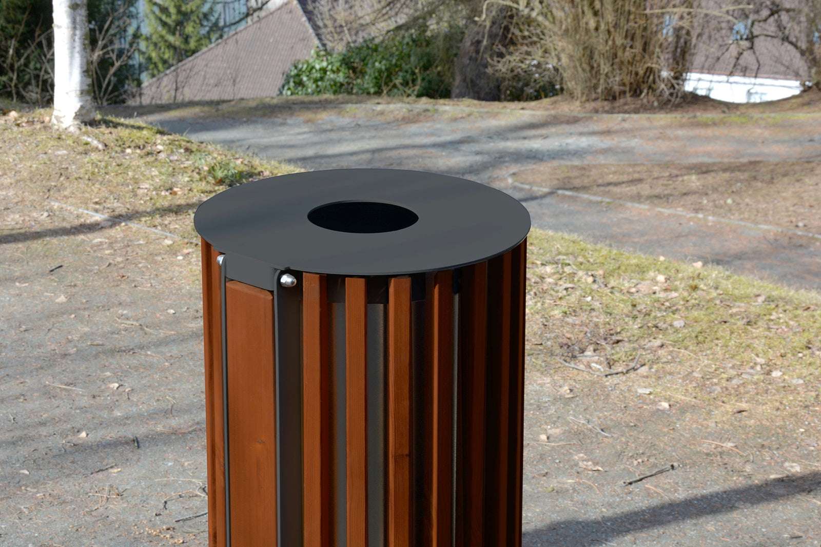 Moderner ZET Abfallbehälter aus Holz und Metall mit runder Öffnung, im Freien aufgestellt, umgeben von Bäumen und Laub.
