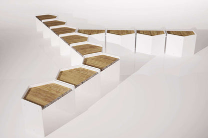 Modulare Sitzbänke mit weißen Seiten und Holzdächern, in einer geometrischen Formation angeordnet.